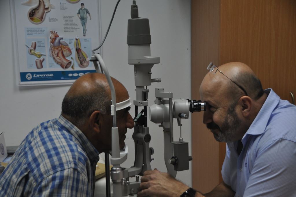 רופא עיניים בודק גבר מבוגר עם מנורת סדק