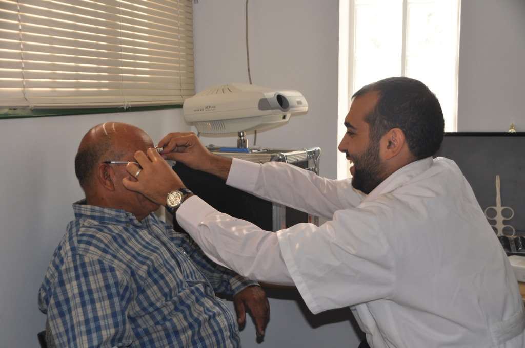 רופא עיניים בודק מטופל במכשיר השלכת אור